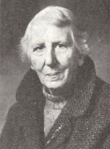 Imagen de Gladys Mitchell en blanco y negro a una edad avanzada, vistiendo abrigo de lana y jersey de cuello alto.