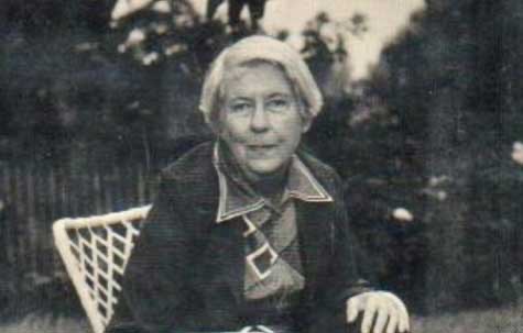 Imagen de Margaret Millar sentada en una silla, en un jardín.