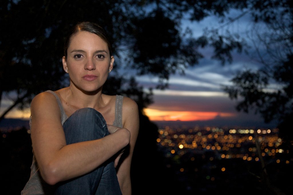 La escritora y periodista Alejandra López González posando con la ciudad de Cali al fondo.
